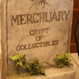 Tombstone-shaped prop with a carved spider at the top, the word 'CRYPT' visible, and ivy growing at the base.